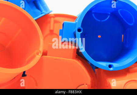 Heap of blue and orange plastic electrical boxes, components for electrical installations, accessories for engineering jobs Stock Photo