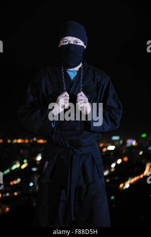 ninja assasin hold katana samurai old martial weapon swordat night with city lights in background Stock Photo