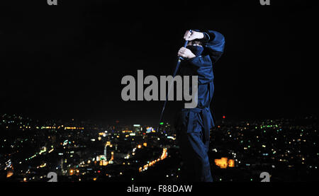 ninja assasin hold katana samurai old martial weapon swordat night with city lights in background Stock Photo