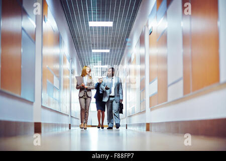 Business people walking down the office corridor and communicating Stock Photo