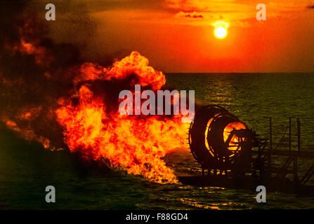 Gas burning flare on offshore oil rig at sunset, Indonesia South East Asia Stock Photo