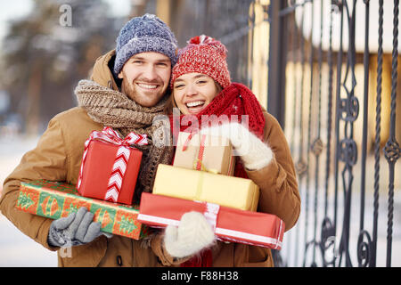 Young dates with wrapped presents looking at camera outdoors Stock Photo