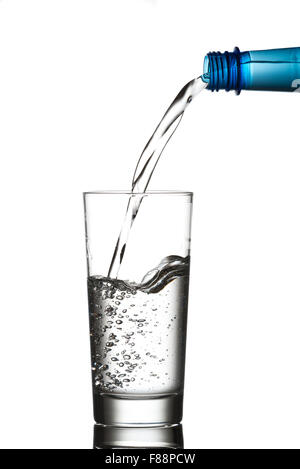 Water pouring from a blue plastic bottle into a drinking glass.  Isolated on white background Stock Photo