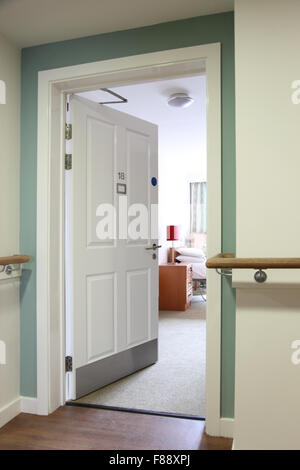 Entrance door to a resident's room in a new, UK care home. Shows fire door accessories and support rails on wall Stock Photo