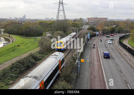 View of London Overground railway line in North London showing two trains and the adjacent road with bus lane and speed camera Stock Photo