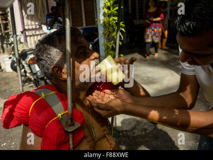 Woman Giving Water To An Hindu Devotee In Annual Thaipusam Religious Festival In Batu Caves, Southeast Asia, Kuala Lumpur, Malaysia Stock Photo