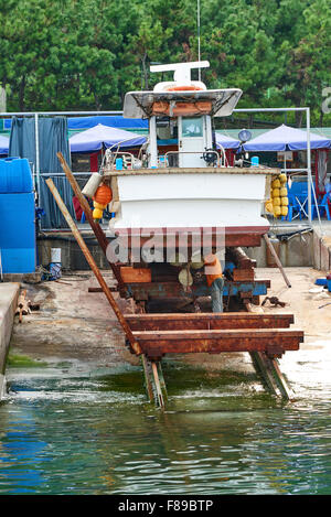 A man removing barnacles on the bottom of fishing boat and screw in a ship yard. Stock Photo