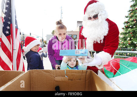 Napa, CA, USA. 5th Dec, 2015. Andrew De Haro, left, Lexi Wagoner, top center, and Bernie Narvaez, dressed as Santa Claus, help Lily Wright donate a board game during the Toys For Tots toy drive by the Napa Marine Core League at Veterans Park in Napa on Saturday. The toy drive will run until December 11. © Napa Valley Register/ZUMA Wire/Alamy Live News Stock Photo