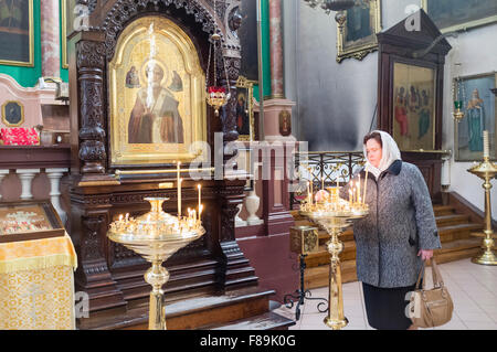 Woman lighting candles inside the Orthodox Church of the Holy Spirit. Vilnius, Lithuania, Europe Stock Photo