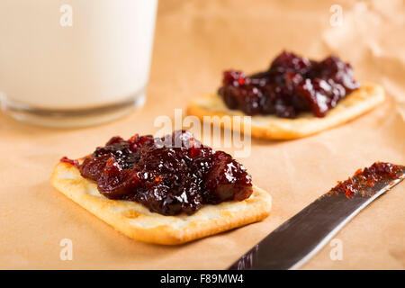 Quince jam on saltine crackers with one glass of milk on paper Stock Photo