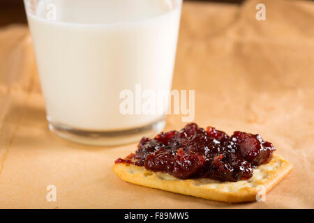 Quince jam on saltine cracker with one glass of milk on paper Stock Photo