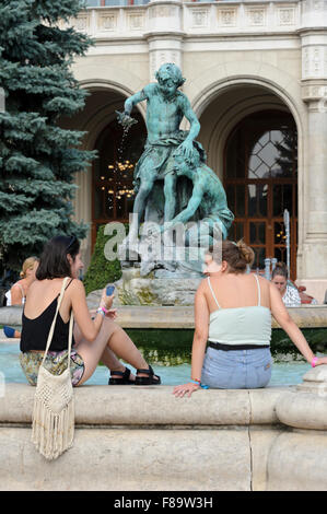A group of young women sitting on the edge of a water fountain with their feet soaking in the cold water, Budapest, Hungary. Stock Photo