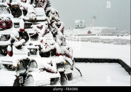 Traditional Maine holiday tree built of lobster traps and fishing gear, with Nubble lighthouse in the background, during a snowstorm in New England. Stock Photo