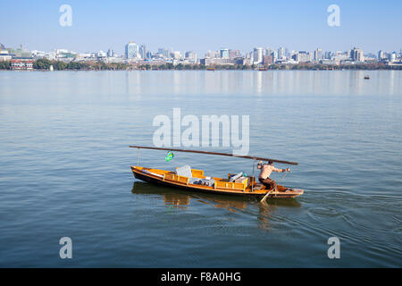 Hangzhou, China - December 5, 2014: Traditional Chinese wooden recreation boat with boatman on the West Lake. Famous park Stock Photo