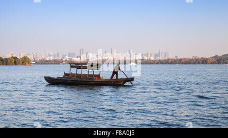 Hangzhou, China - December 5, 2014: Traditional Chinese wooden recreation boat with boatman on the West Lake. Famous park Stock Photo