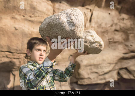 Strong child holds heavy stones. Stock Photo