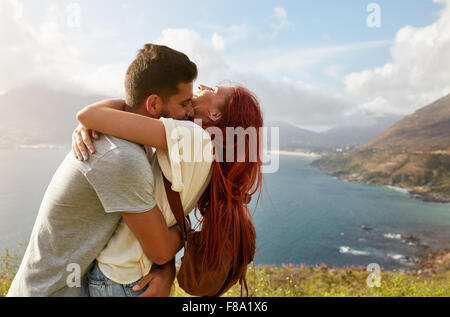 Loving young couple embracing and kissing on a summer day outdoors. Man hugging his girlfriend. Enjoying their summer vacation. Stock Photo