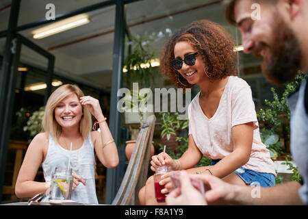 Three friends sitting at sidewalk cafe and playing cards. Relaxed young people at coffee shop enjoying in their free time. Women Stock Photo