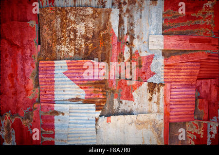 An abstract background image of the flag of Canada painted on to rusty corrugated iron sheets overlapping to form a wall Stock Photo