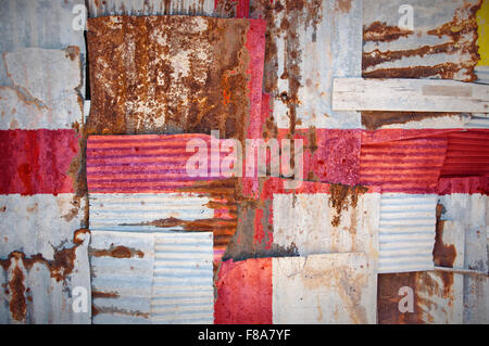 An abstract background image of the flag of England painted on to rusty corrugated iron sheets overlapping to form a wall Stock Photo