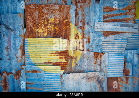 An abstract background image of the flag of Palau painted on to rusty corrugated iron sheets overlapping to form a wall or fence Stock Photo