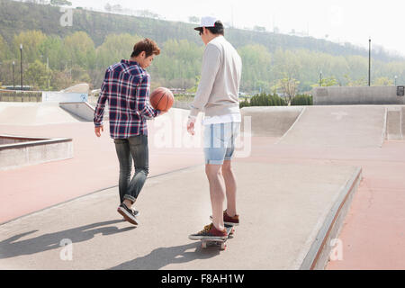 Man on skateboard and the other man with a basketball Stock Photo