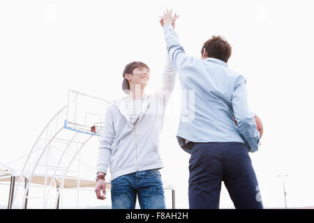 Low angle of two men giving a high-five Stock Photo