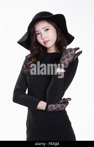 Young woman in black hat and black dress wearing lace gloves staring forward Stock Photo
