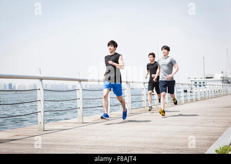 Three young men in sportswear running along the riverside at the Han river park Stock Photo