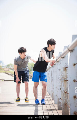 Two young men leaning on the fence at the riverside in Han river park and taking a rest Stock Photo