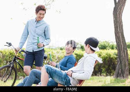 Three young men having fun at the park holding beer bottles Stock Photo