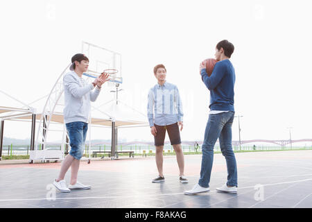 Three young men standing at the basketball court Stock Photo
