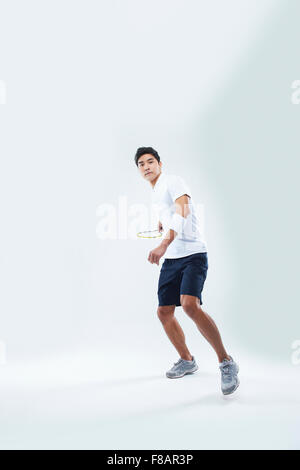 Man in sportswear standing and swinging a tennis racket with a hand staring at front Stock Photo