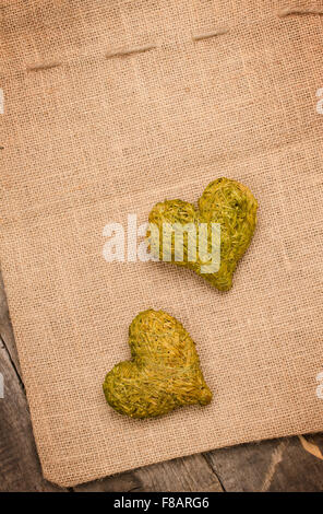 Two green heart shapes of hay on a rustic wooden background Stock Photo
