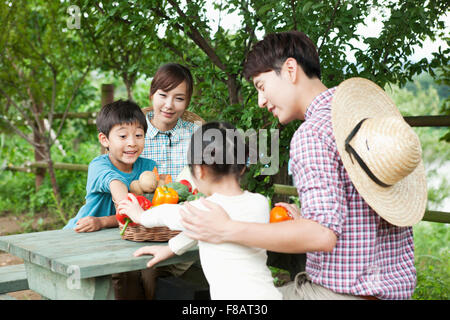 Portrait of harmonious family sitting at table with fresh vegetables in the open air Stock Photo