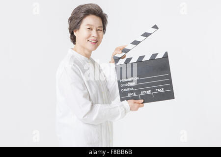 Grandmother with short hair holding a clapperboard and smiling Stock Photo
