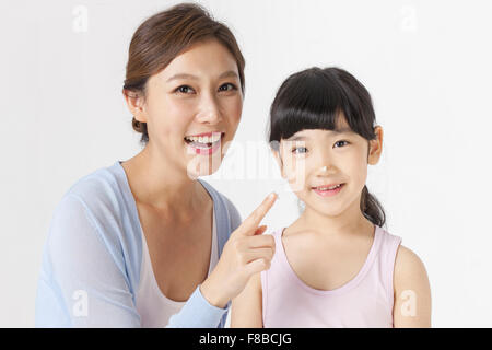 Mother smiling with a contact lens on her finger and daughter staring forward with a smile Stock Photo