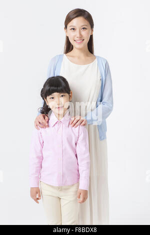 Mother standing behind her daughter with her hands on daughter's shoulder both staring forward with a smile Stock Photo