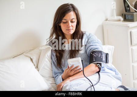 Woman taking her blood pressure with a portable blood pressure monitor. Stock Photo