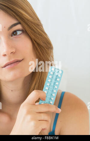 Young woman holding oral contraception pills.