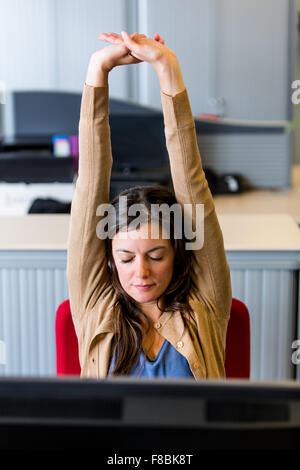 Office woman stretching arms at work. Stock Photo