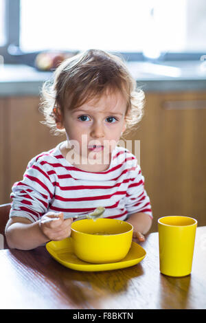24 month old baby girl eating alone. Independence training. Stock Photo