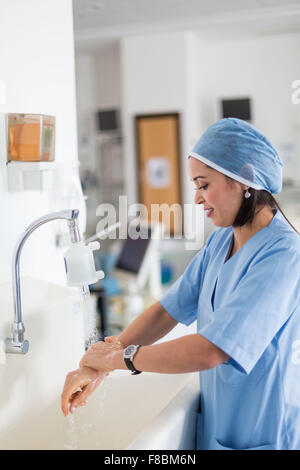 Nurse washing her hands at a sink. Stock Photo