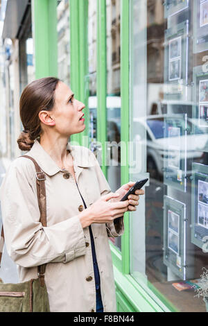 Woman looking for ads in a real estate agency. Stock Photo