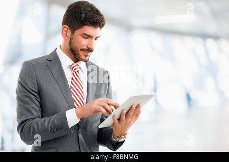 Portrait of young broker standing at office while holding digital tablet in his hands. Young businessman touching digital tablet Stock Photo