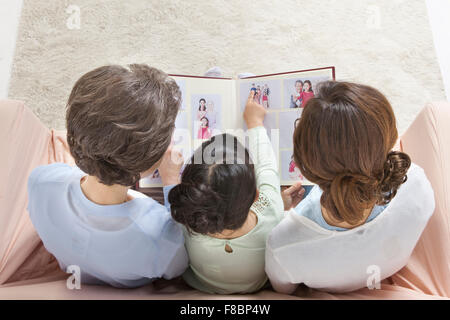 High angle of mother, daughter, and granddaughter looking at the photo album together Stock Photo