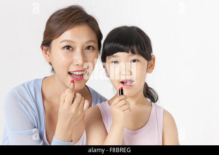 Young girl and her mother putting on lipstick Stock Photo