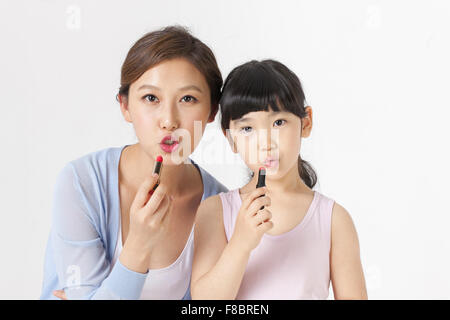 Young girl and her mother putting on lipstick Stock Photo