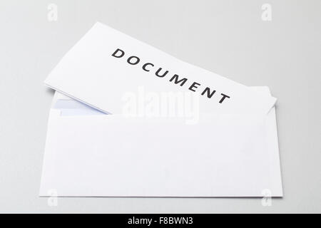 Folded white sheets document put in blank white envelope, isolated on background. Stock Photo