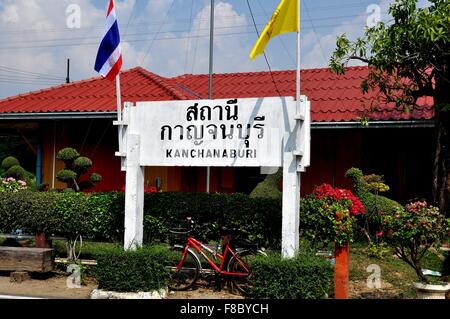 Kanchanaburi, Thailand:  Sign and Thai flags in front of the small Kanchanaburi railway station Stock Photo